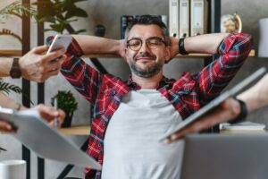 Joyful businessman in casual sitting in his office and resting from work from multitasking